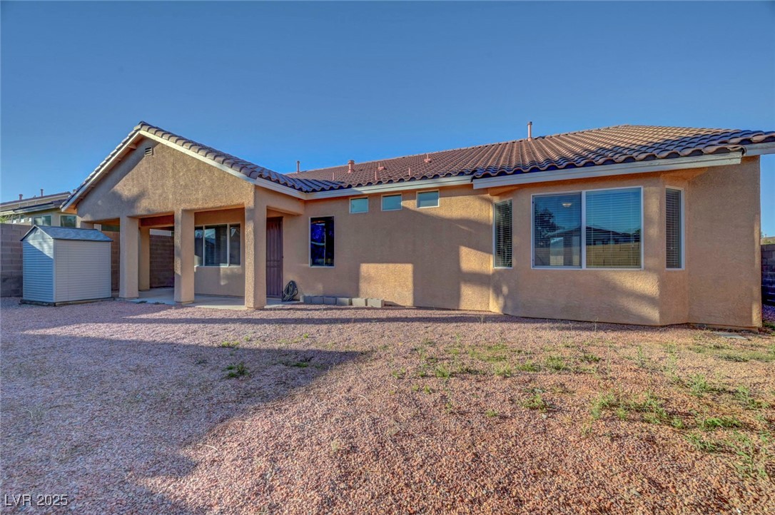 9417 Wisdom Valley Avenue Las Vegas, NV 89149 - Photo 65 of 67 Rear view of property with a patio, stucco siding, a storage unit, and a tiled roof
