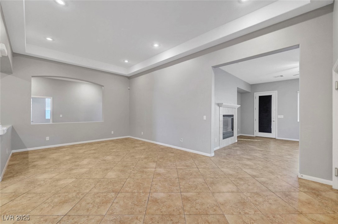 9417 Wisdom Valley Avenue Las Vegas, NV 89149 - Photo 8 of 67 Spare room with a raised ceiling, a fireplace, recessed lighting, and light tile patterned flooring