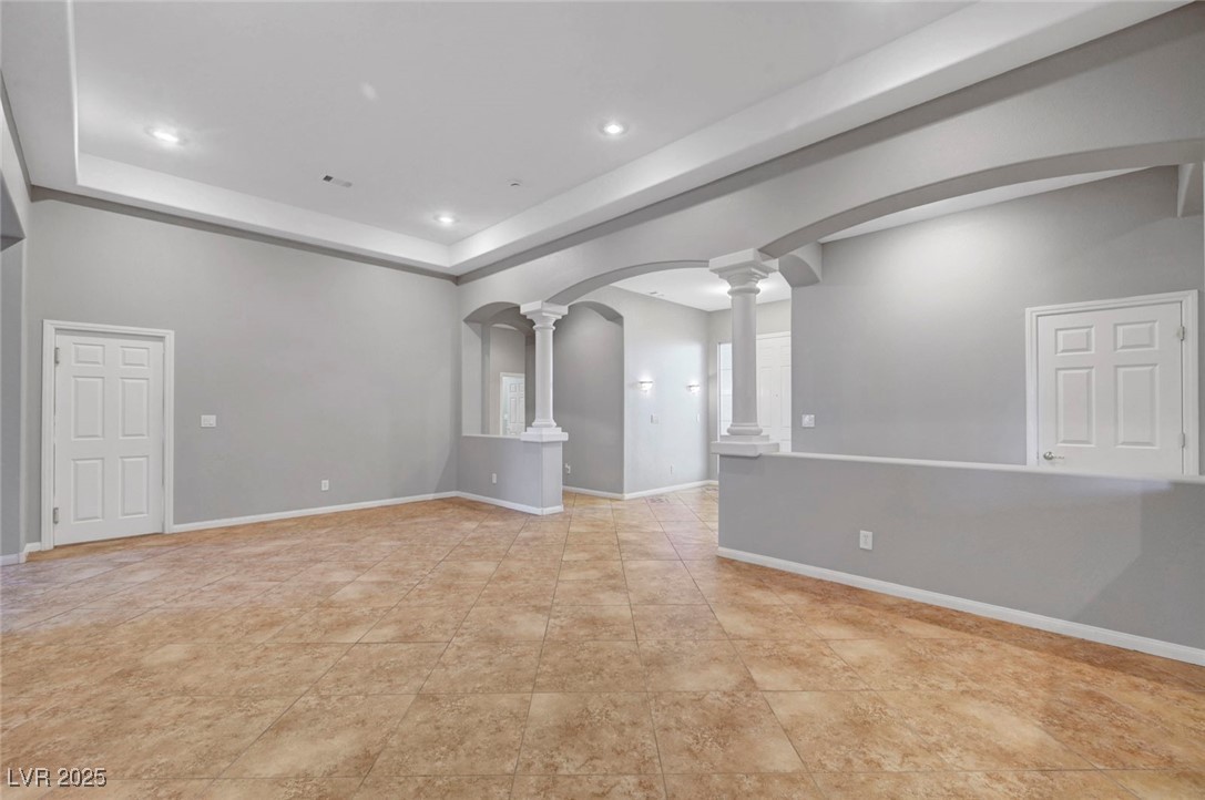 9417 Wisdom Valley Avenue Las Vegas, NV 89149 - Photo 10 of 67 Empty room featuring ornate columns, arched walkways, a raised ceiling, recessed lighting, and light tile patterned floors