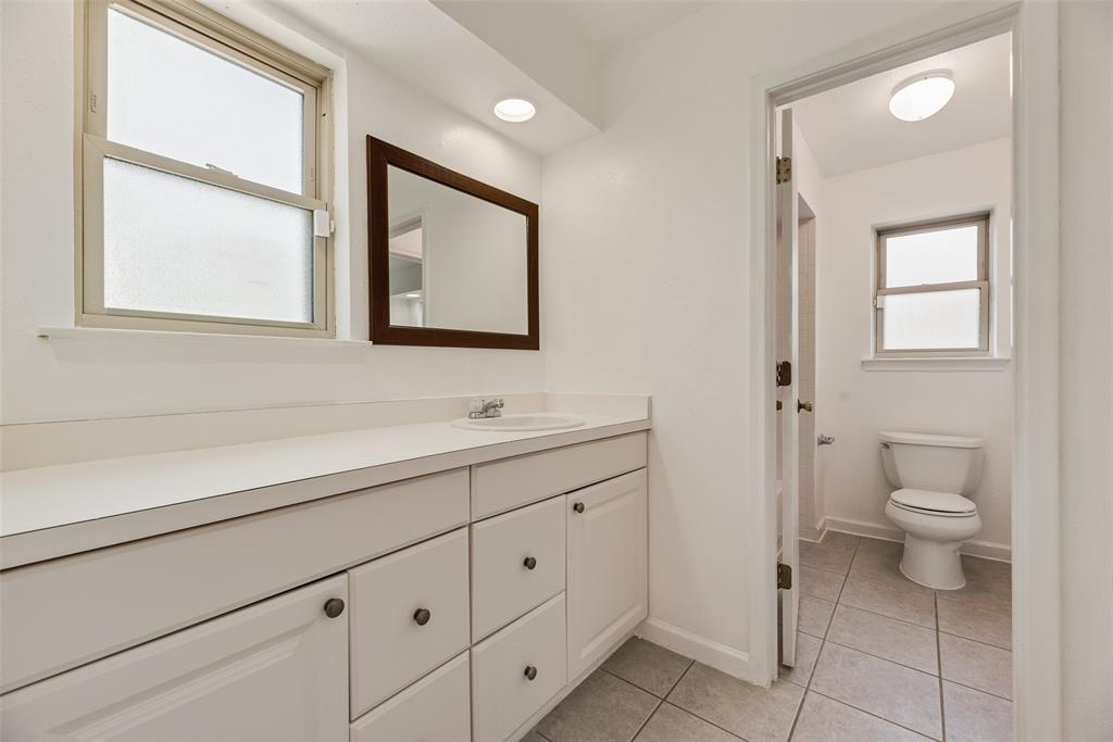 4988 Thunder Road Dallas, TX 75244 - Photo 21 of 32 Bathroom featuring a white vanity with integrated sink, a framed wall mirror, and two windows with frosted glass