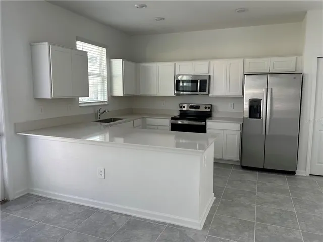 a kitchen with stainless steel appliances a refrigerator a sink a stove a microwave a counter top and cabinets