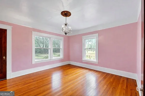 a view of an empty room with wooden floor and a window