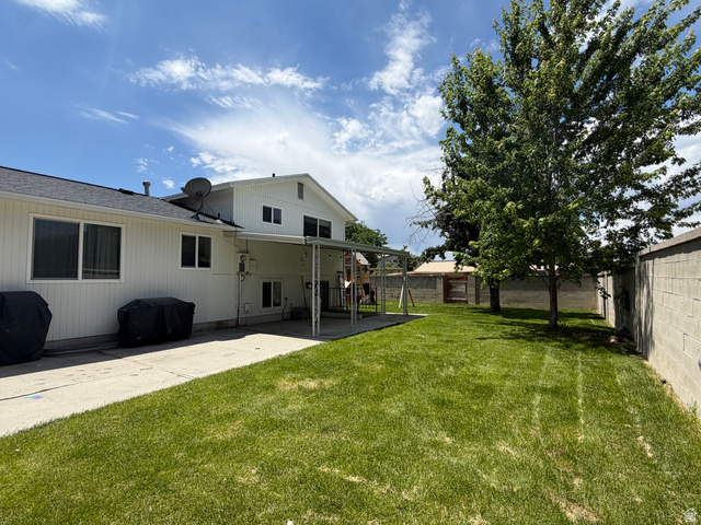375 East 10560 South Sandy, UT 84070 - Photo 2 of 21 Expansive backyard featuring a concrete patio, covered patio area, lush green lawn, mature trees, and concrete block perimeter fencing