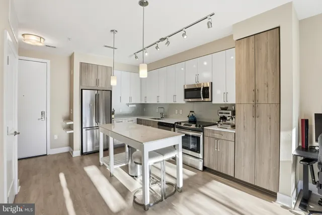 a kitchen with stainless steel appliances a stove a refrigerator a oven a sink with a dining table and chairs