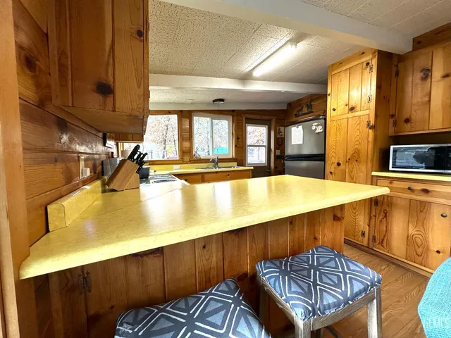 a kitchen with stainless steel appliances kitchen island granite countertop a table chairs in it and a window