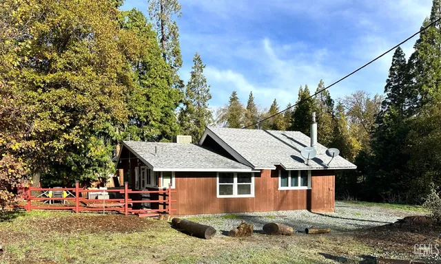 a view of a big house with a fountain plants and large tree