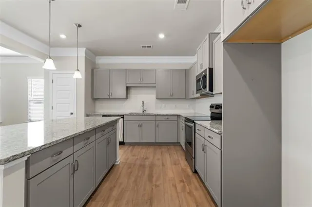 a kitchen with kitchen island granite countertop a sink cabinets and stainless steel appliances