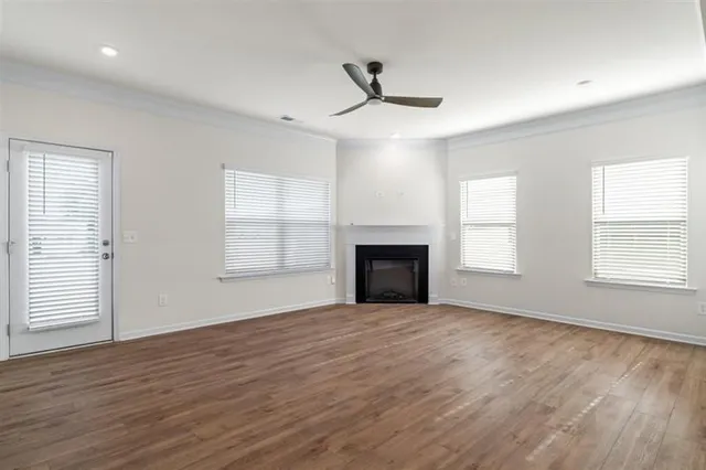 an empty room with wooden floor fireplace and windows