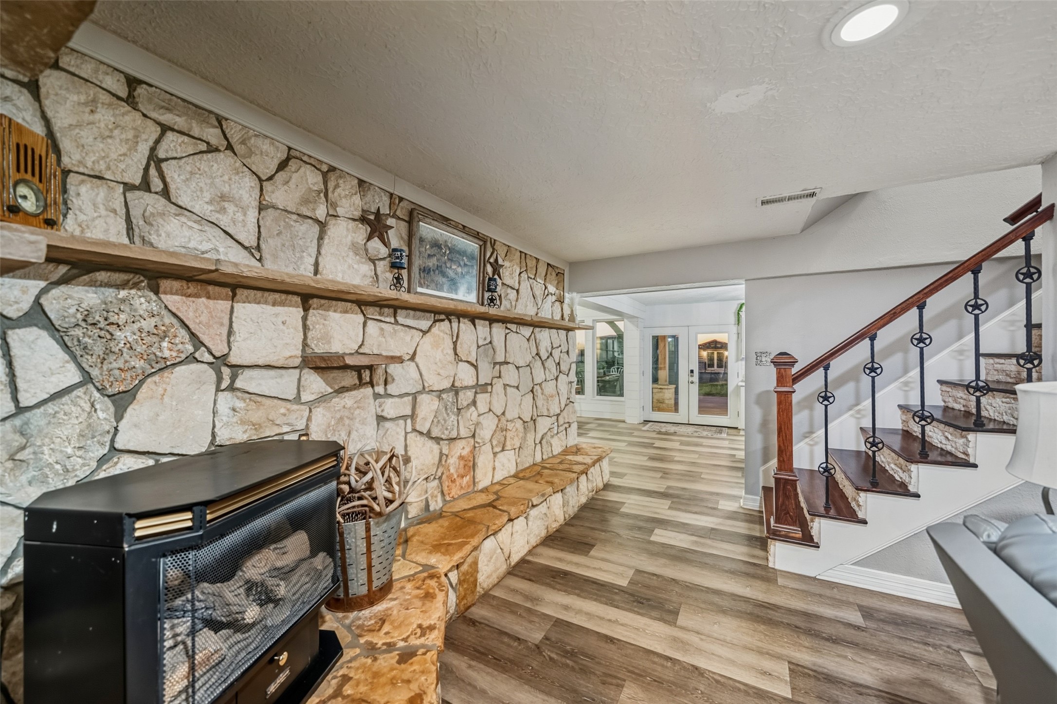 19989 Meadow Bend Road Hempstead, TX 77445 - Photo 13 of 35 Natural stone fireplace creates a strong focal point, complemented by adjacent stairway with wood treads and iron balusters.