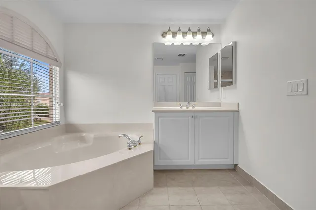 a bathroom with a tub sink and mirror