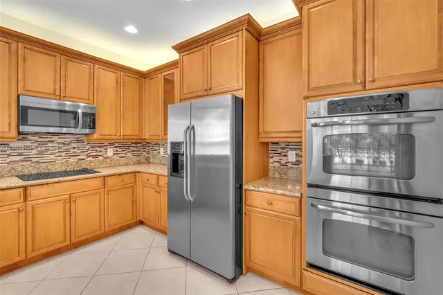 a kitchen with stainless steel appliances granite countertop a refrigerator and a stove top oven