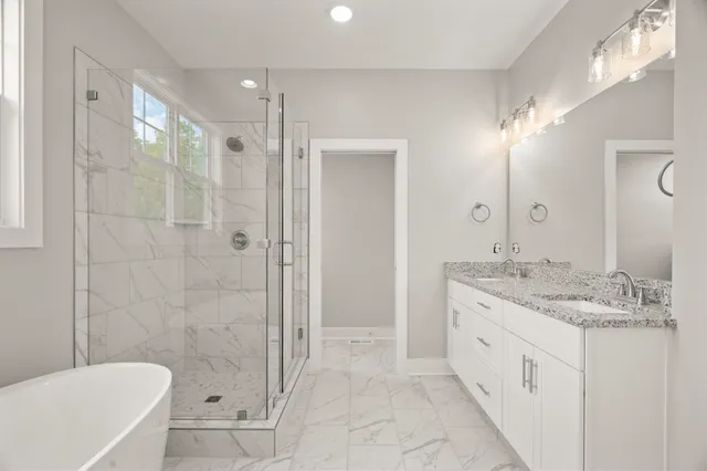 a bathroom with a granite countertop sink a mirror a bathtub and shower