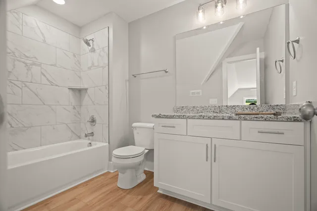 a bathroom with a granite countertop sink toilet a mirror and bathtub