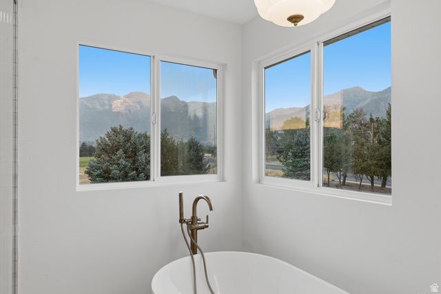 702 Alpine Highway Alpine, UT 84004 - Photo 52 of 83 Freestanding soaking tub with a floor-mounted bronze-finish faucet, positioned below two large windows with mountain and tree scenery