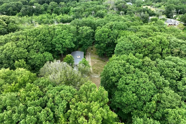 an aerial view of residential house with outdoor space and trees all around