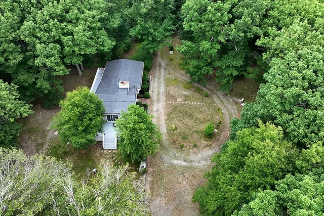 an aerial view of a house with a yard and large tree