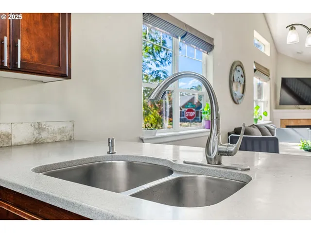 a view of kitchen sink a faucet a fireplace and a granite countertops with wooden floor