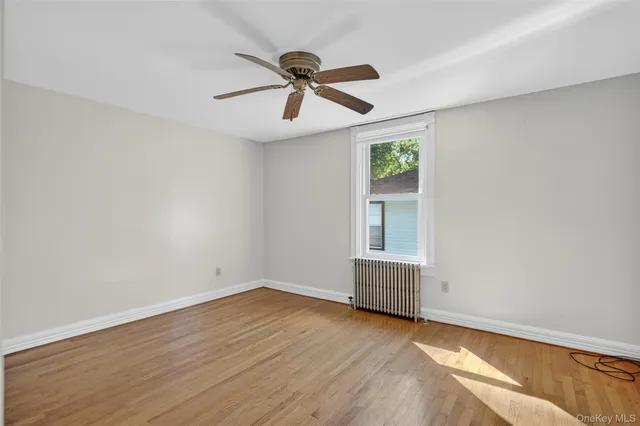 an empty room with wooden floor ceiling fan and windows
