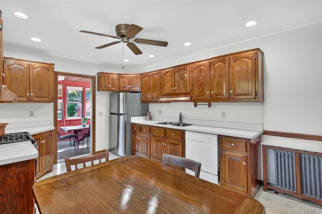 a kitchen with stainless steel appliances granite countertop a refrigerator a sink dishwasher a dining table and chairs with wooden floor