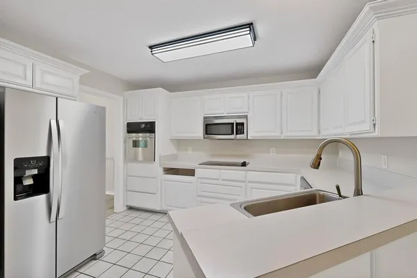 a kitchen with white cabinets and refrigerator