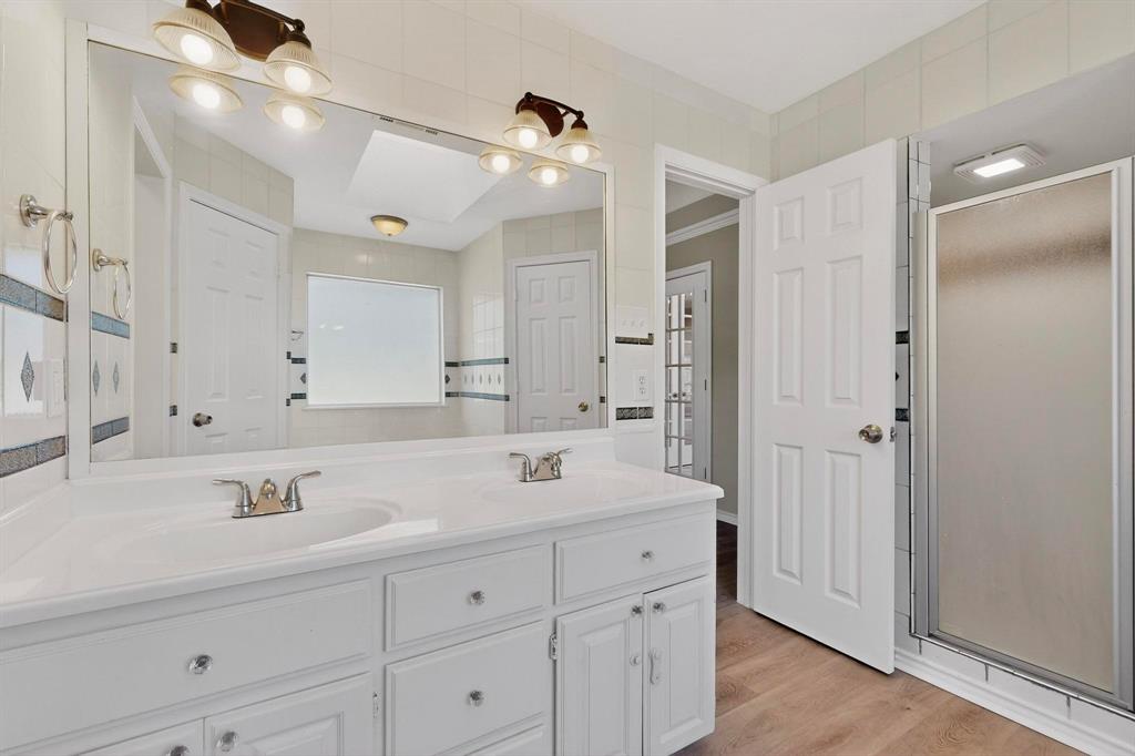 2601 Trail Tree Court Burleson, TX 76028 - Photo 23 of 40 Bathroom with double vanity, light wood finished floors, and a stall shower