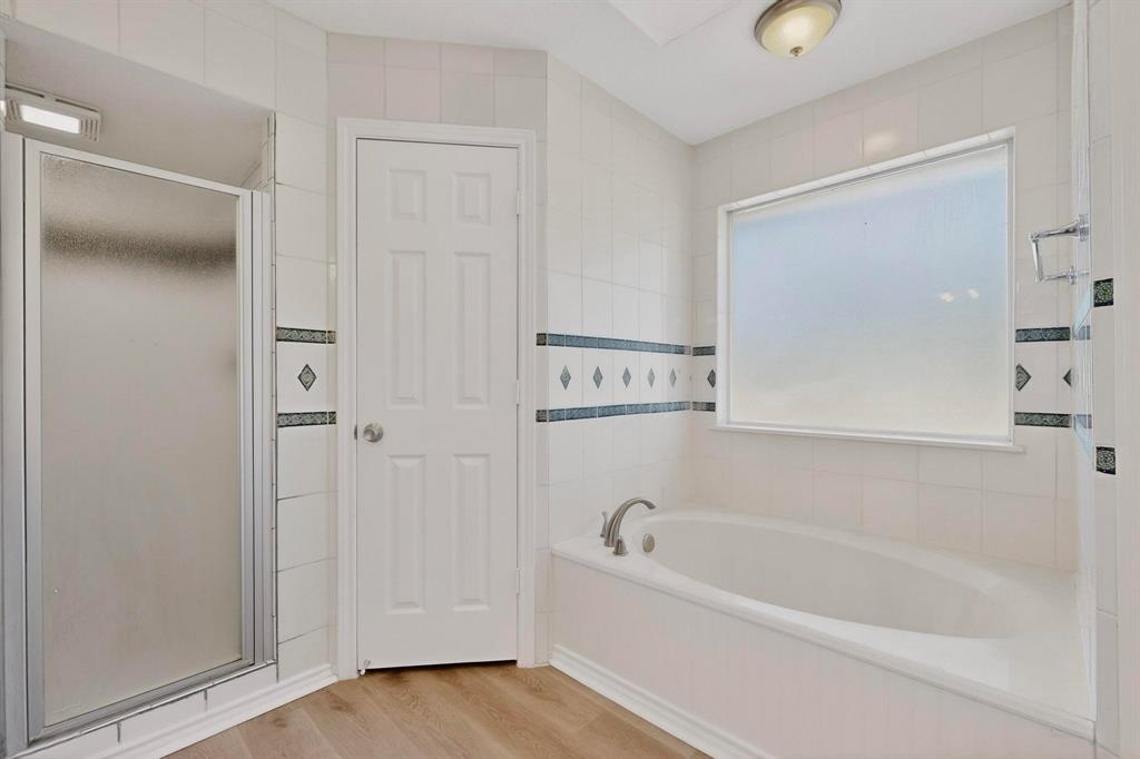 2601 Trail Tree Court Burleson, TX 76028 - Photo 25 of 40 Full bathroom with a bath, a stall shower, light wood finished floors, and tile walls