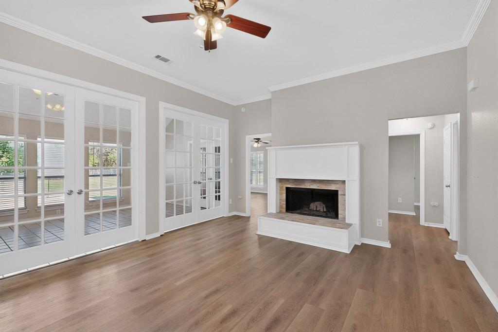 2601 Trail Tree Court Burleson, TX 76028 - Photo 9 of 40 Unfurnished living room with ceiling fan, french doors, ornamental molding, a fireplace with raised hearth, and dark wood finished floors