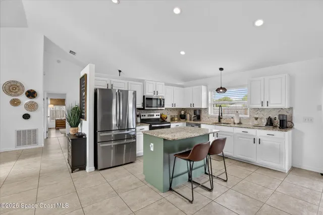 a large kitchen with granite countertop a sink counter space stainless steel appliances and cabinets
