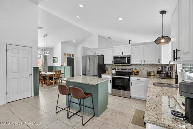 a kitchen with stainless steel appliances granite countertop a sink dishwasher stove and refrigerator with wooden floor