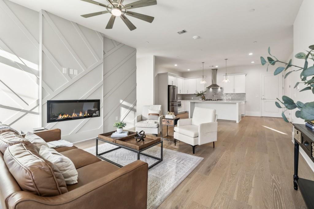 a living room with furniture kitchen view and a wooden floor