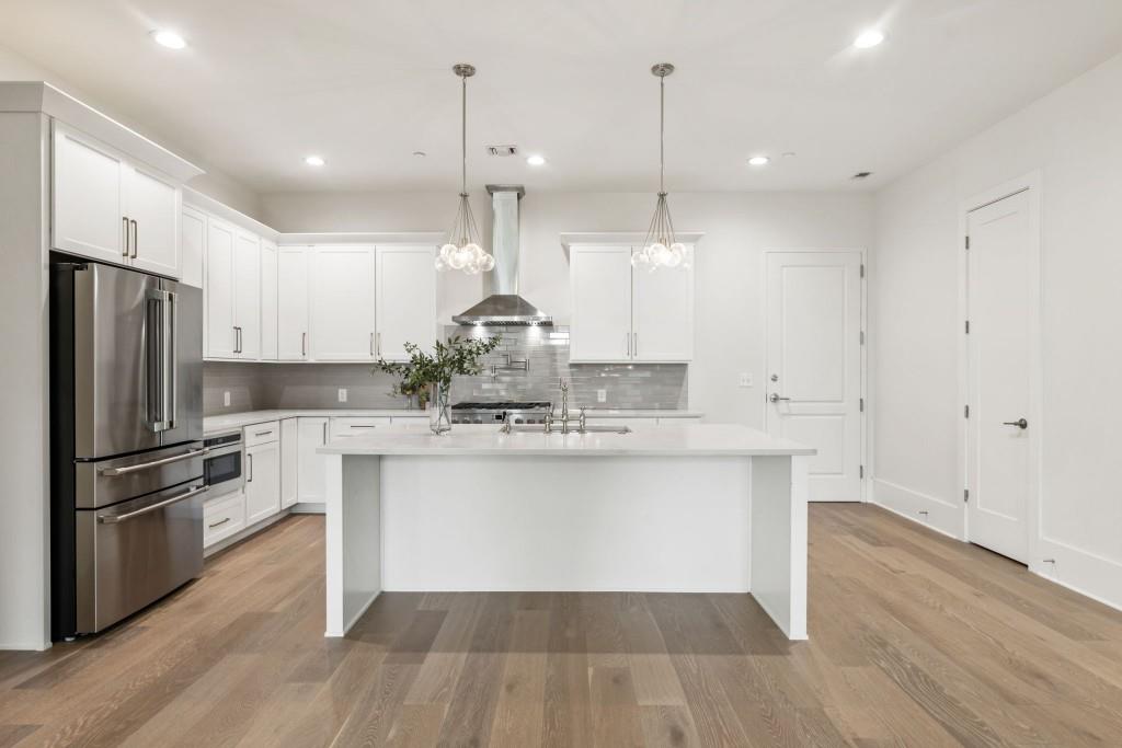 12455 Broadwell Road, Unit 202 Milton, GA 30004 - Photo 8 of 31 a kitchen with kitchen island a sink a stove a refrigerator and wooden floor