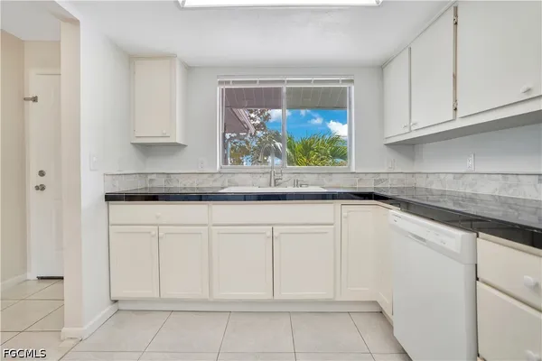 a kitchen with white cabinets and window