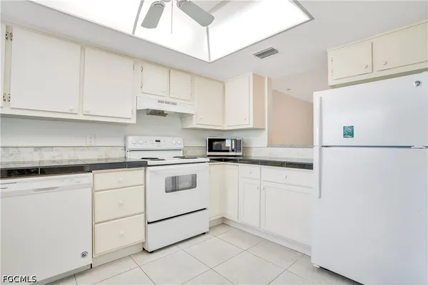 a kitchen with granite countertop white cabinets and white appliances