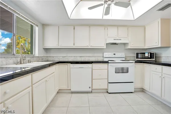 a kitchen with cabinets appliances a sink and a window