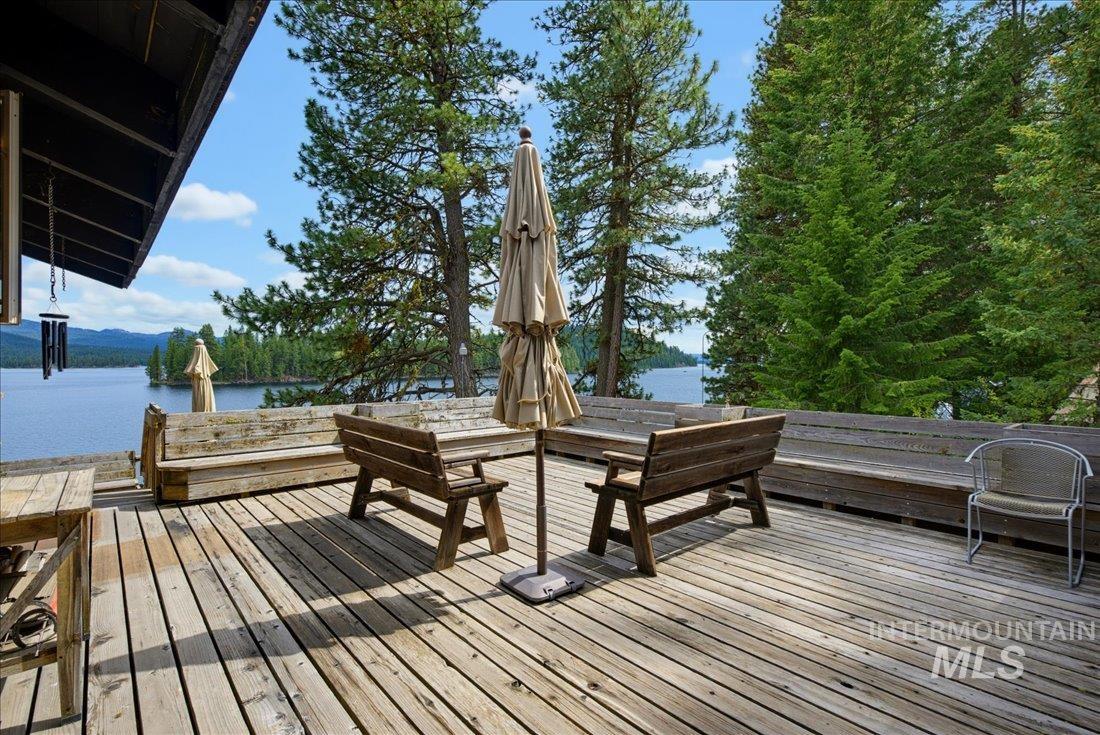 3800 Warren Wagon Road McCall, ID 83638 - Photo 29 of 50 Spacious wood deck with built-in bench seating, featuring prominent water frontage and surrounding mature evergreen trees