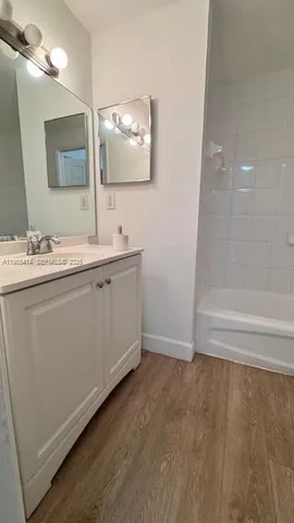 a bathroom with a double vanity sink mirror and bathtub