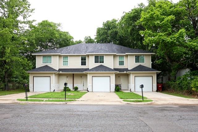 802 South 5th Street, Unit 1 Bonham, TX 75418 - Photo 2 of 25 Two-story residential building featuring light-colored siding, individual garage doors, and covered entryways