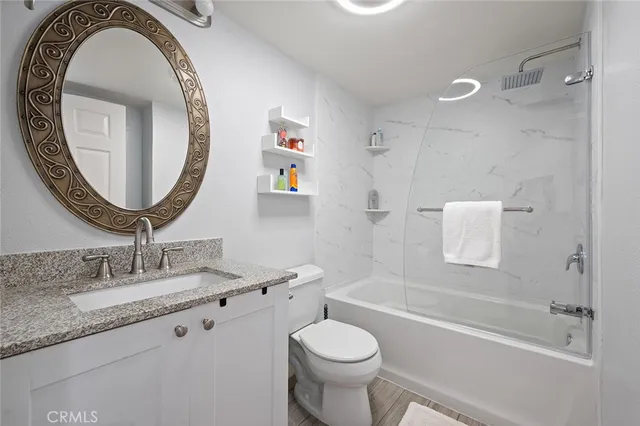 a bathroom with a granite countertop toilet a sink and a mirror