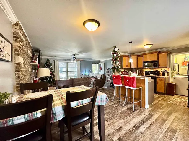 a room with stainless steel appliances kitchen island granite countertop a dining table chairs and a sink
