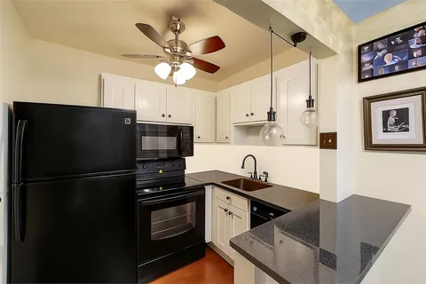 a kitchen with stainless steel appliances granite countertop a refrigerator a sink a stove and black cabinets