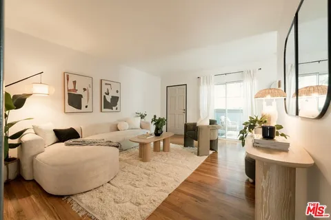 a living room with couches a coffee table and painting on the wall with wooden floor