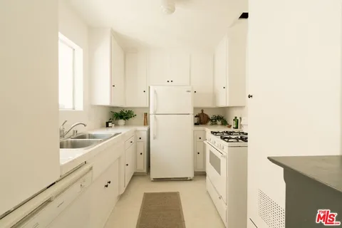 a kitchen with granite countertop white cabinets and white appliances