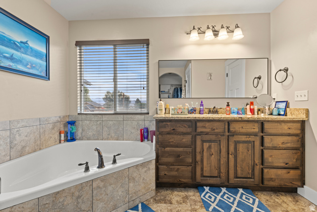 4557 North Ranch Road East Tooele, UT 84074 - Photo 20 of 43 Built-in soaking tub with tile surround, vanity, and a large wall-mounted mirror