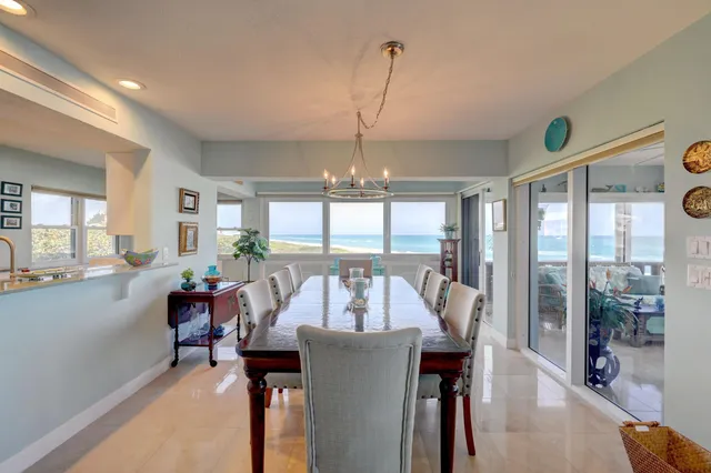 a view of a dining room and livingroom with furniture wooden floor a rug a painting and a chandelier