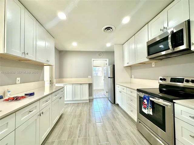a large kitchen with stainless steel appliances granite countertop a stove and a sink