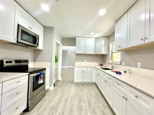 a kitchen with stainless steel appliances white cabinets sink and a microwave