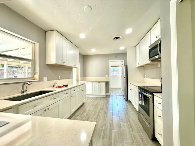 a large kitchen with stainless steel appliances lots of counter space and a sink