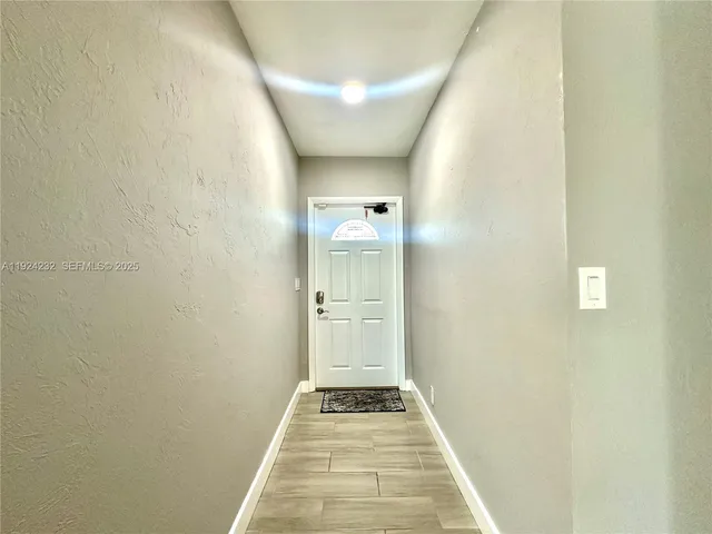 a view of a hallway with wooden floor and a bathroom