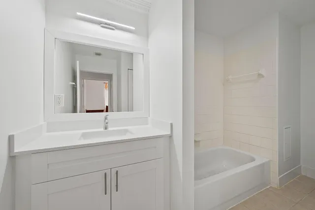 a bathroom with a tub sink and mirror
