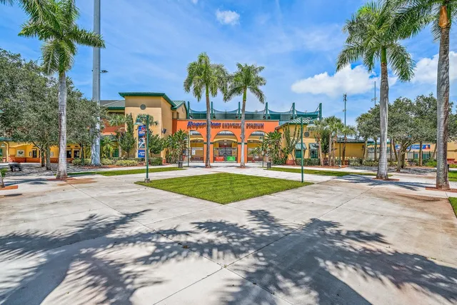 a view of a building with a big yard and palm trees